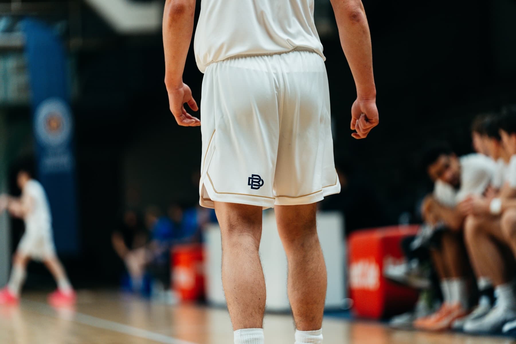 Detail of cream Berlin Dreams shorts with navy monogram logo, seen from behind