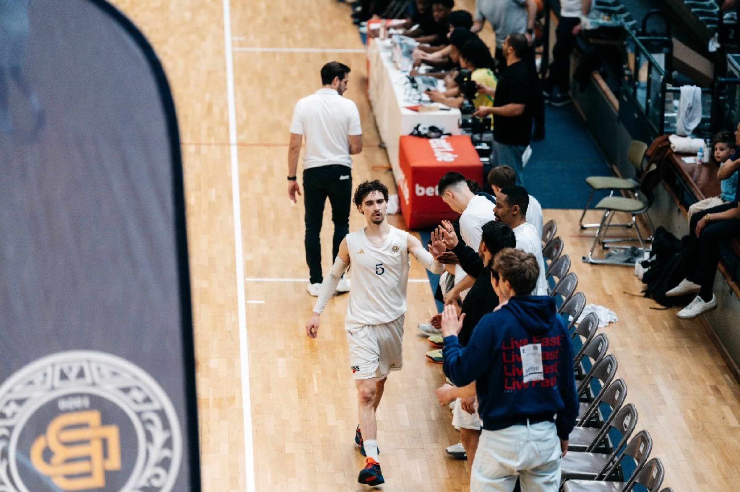 Player number 15 high-fiving the bench along the sideline, blue banner in the foreground