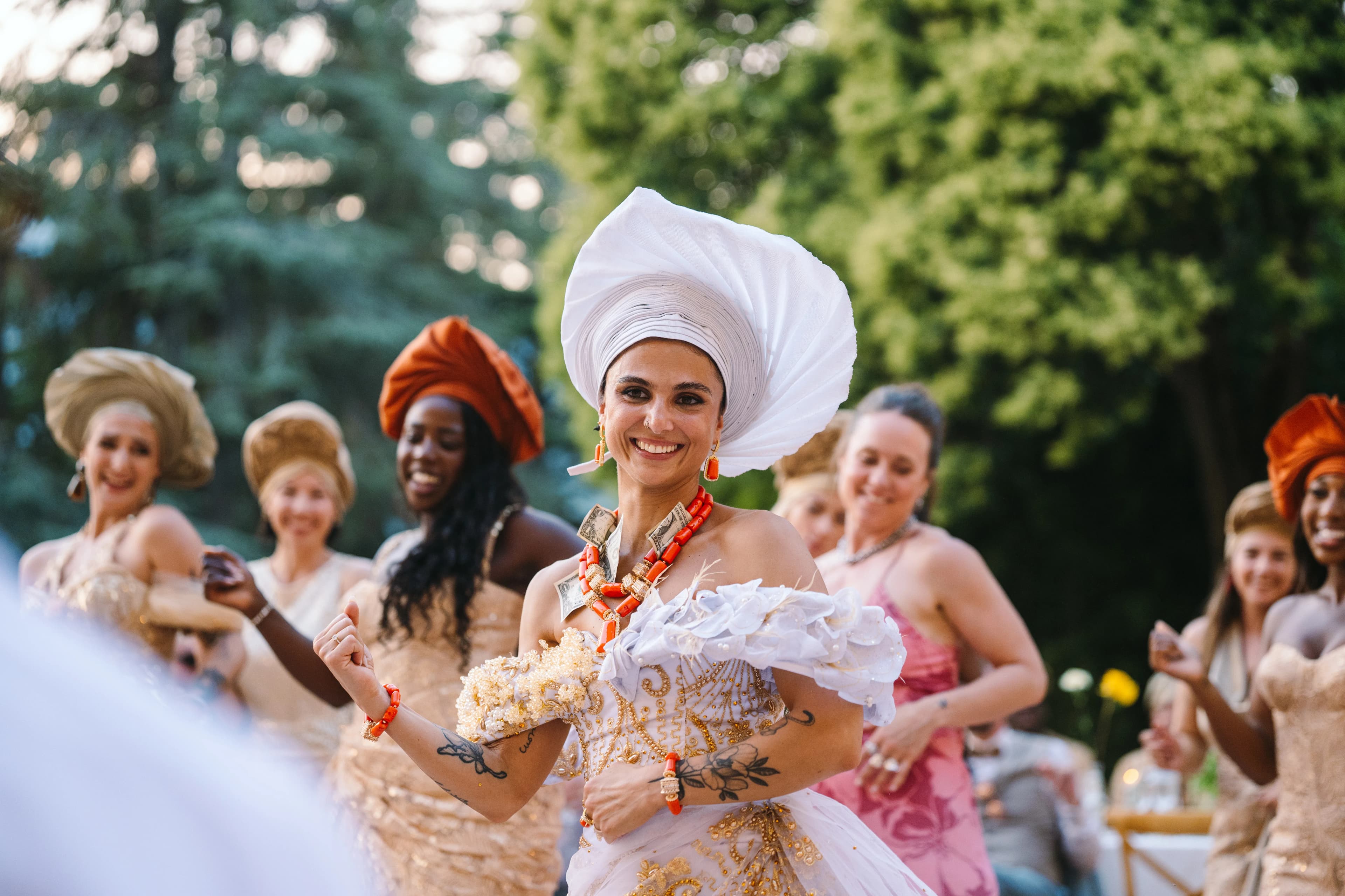 Bride in a white headwrap in front of guests outdoors, Isa and Madu’s wedding
